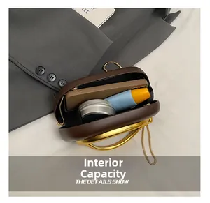 Macro shot showing internal capacity of brown leather clutch bag with gold round handle