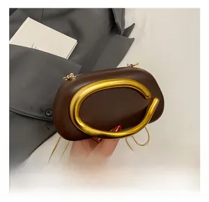 Detail of dark brown leather cloud bag with large golden C-handle and fine chain strap