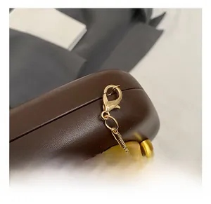 Detailed close-up of premium gold hook and chain on dark brown leather evening bag