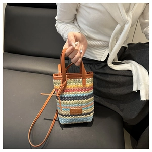 Détail du sac seau tissé à rayures colorées avec poignée en cuir et écusson