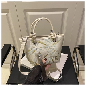Détail de la broderie de feuilles de bambou sur sac crème avec pompon en perles de jade
