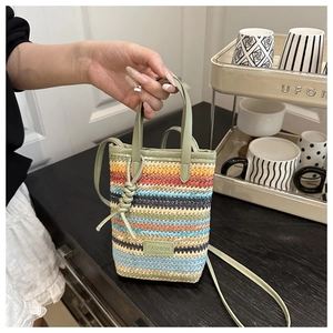 Détail du sac bandoulière tissé à rayures colorées avec étiquette FASHION et anse verte