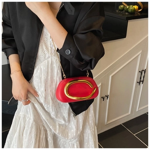 Detail of red leather mini bag with gold metal C logo being held by a model
