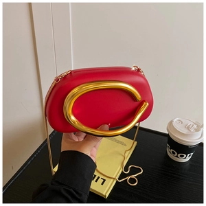 Close-up of vibrant red crossbody bag with oversized gold circular metal handle and chain