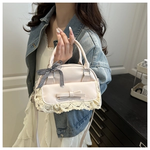 Detail of cream lace handbag with bow decoration and black and white checkered ribbon handle