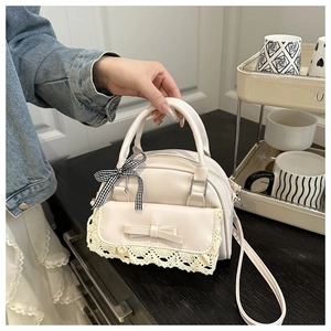 Detail of cream faux leather handbag with lace trim, bow, and gingham ribbon accents