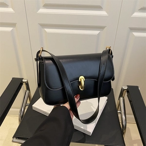 Minimalist black glossy leather shoulder bag with a gold oval twist lock and adjustable strap