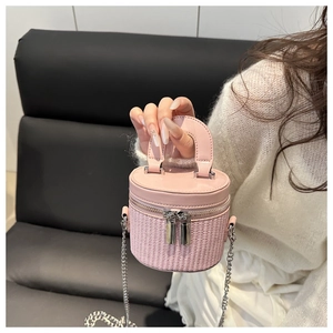 Pink bucket bag with woven bottom, dual metal zippers, and thin chain strap detail