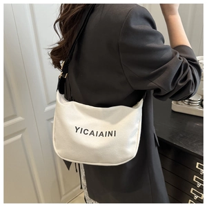 Detail of white canvas shoulder bag featuring black letter print and adjustable strap