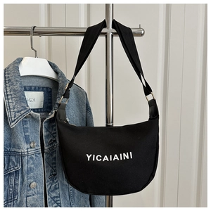 Detail of a black canvas crescent tote bag with YICAIAINI text hanging on a rack