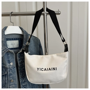 Detail of white canvas half-moon bag featuring wide shoulder strap and YICAIAINI logo