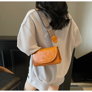 Close-up of orange brown retro crossbody bag with a patterned woven shoulder strap