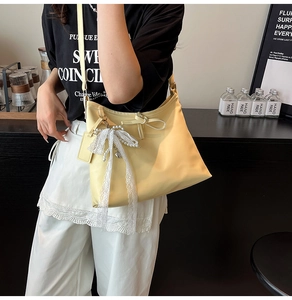 Detail of light yellow tote bag with white lace bow, pearls and heart pendant charm