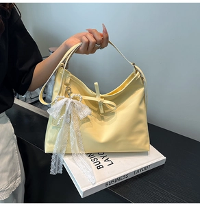 Detail of yellow faux leather tote bag with lace bow and elegant pearl charm