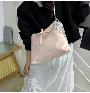 Detail of pink shoulder tote bag with ribbon bow and lace pearl charm accessory