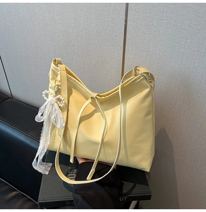 Detail of light yellow PU leather tote bag with elegant pearl and lace bow charm