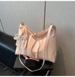 Detail of light pink tote bag with pearl woven bow and lace pendant accessory