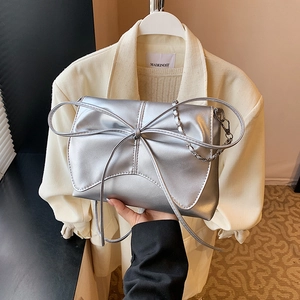 Silver metallic shoulder bag featuring a large decorative bow and elegant chain strap