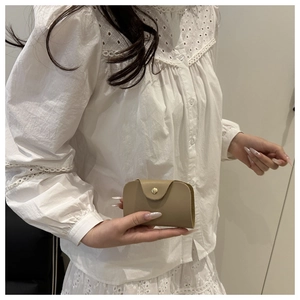 Close-up of khaki envelope card holder with gold snap button in model's hand