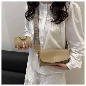 Close-up of khaki envelope crossbody bag with patterned wide strap on a female model