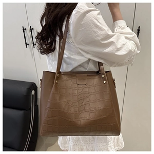 Detailed shot of brown crocodile embossed tote bag with gold rivets on shoulder straps