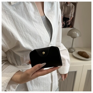 Close-up of minimalist black matte leather card wallet with gold snap button detail