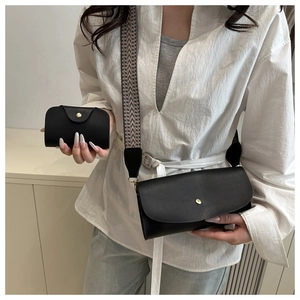 Detail of black pebbled leather handbag with colorful geometric woven wide shoulder strap