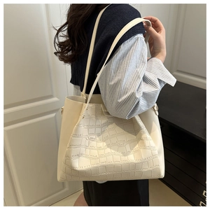 Detail showing the crocodile pattern texture on a beige tote bag worn by a model