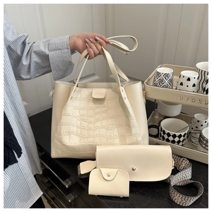 Three-piece set featuring cream faux leather tote with crocodile texture and geometric strap
