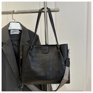 Detail of black crocodile embossed tote bag with adjustable geometric pattern strap