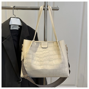 Detail of beige crocodile embossed tote bag with woven shoulder strap and gold hardware