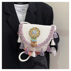 Detail of bohemian saddle bag with colorful beads, ethnic embroidery and long purple tassels