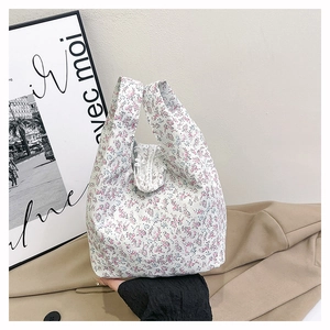 Detail of floral canvas tote bag featuring delicate pink flowers and white lace trim