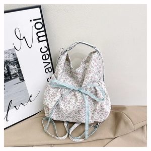 Detailed close-up of floral canvas tote bag featuring a blue plaid bow and snap button