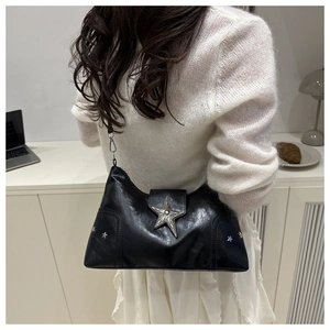 Detail of black leather underarm bag featuring large silver star stud and metal hardware