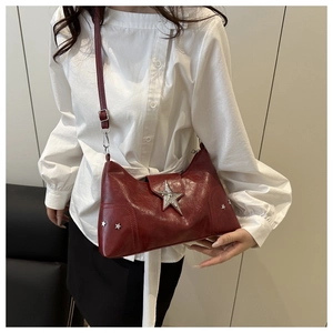 Detail of burgundy glossy crossbody bag featuring large silver star and punk studs