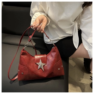 Detailed view of red glossy shoulder bag featuring silver star rivets and metal star buckle