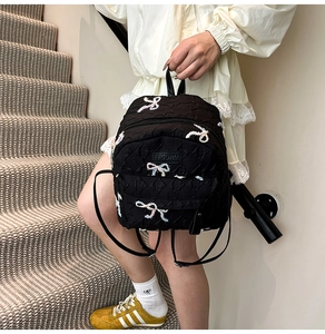 Detail of black quilted backpack with butterfly embroidery and F-pattern texture