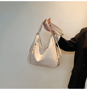 Close-up of cream large tote bag with adjustable shoulder straps and silver metal hardware