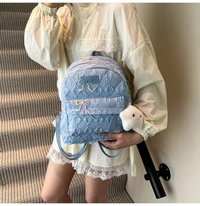 Detail of light blue quilted backpack with butterfly embroidery and star charm