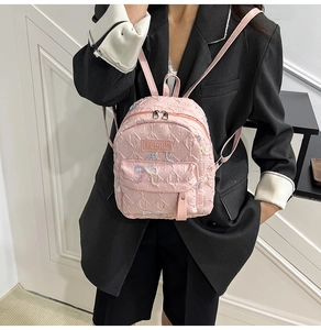 Detail of pink quilted mini backpack with sequined bows and F-letter embossed texture