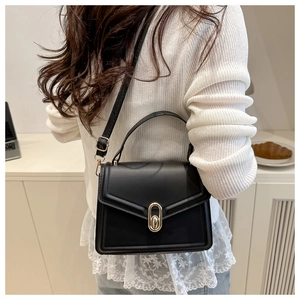 Detail van zwarte crossbodytas met gouden draaisluiting en mat lederen textuur