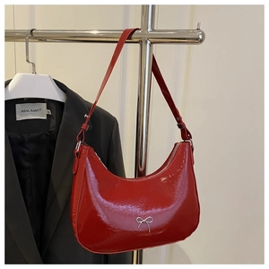 Close-up of red patent leather crescent bag with silver metallic bow detail