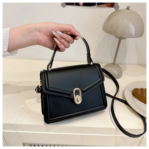 Detail van zwarte kunstlederen crossbodytas met gouden ovale sluiting en handvat