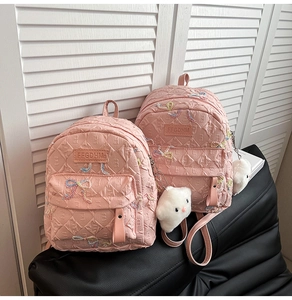 Detail of pink quilted mini backpacks with sequin bows and plush cloud charms