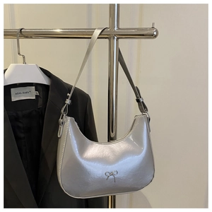 Detailed view of silver mirror finish underarm bag with decorative metal bow