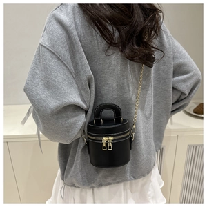 Back view of a mini black cylindrical crossbody bag with gold chain and white stitching