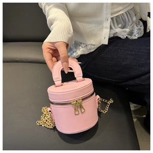 Detailed close-up of a pink bucket bag featuring golden zippers and chain strap