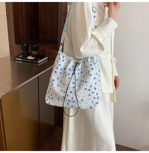 Detail of floral nylon shoulder bag featuring blue flowers and adjustable drawstring closure