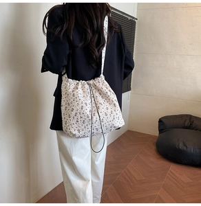 Detailed close-up of floral nylon bucket bag with drawstring and wide shoulder strap